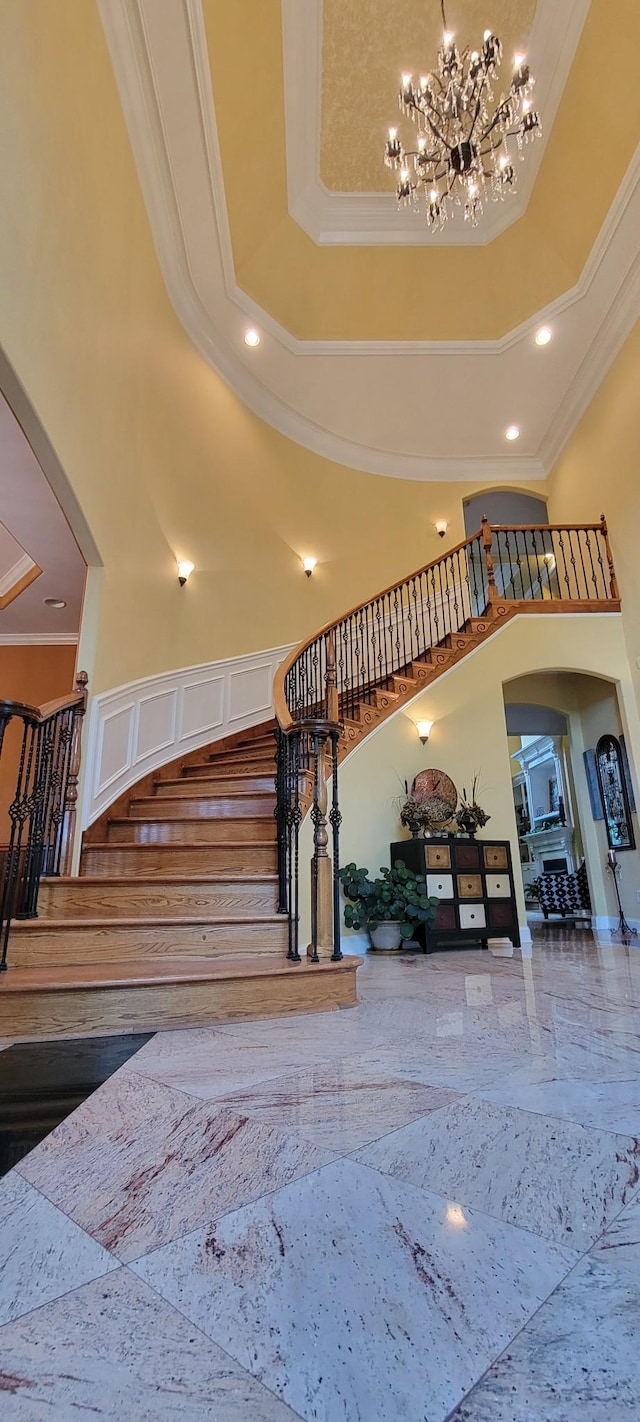 stairs with a high ceiling, a tray ceiling, and crown molding