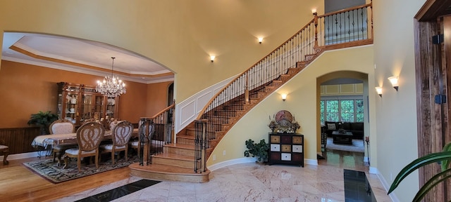 stairway with a high ceiling, an inviting chandelier, and crown molding