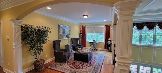 living area featuring ornamental molding, hardwood / wood-style floors, and ornate columns