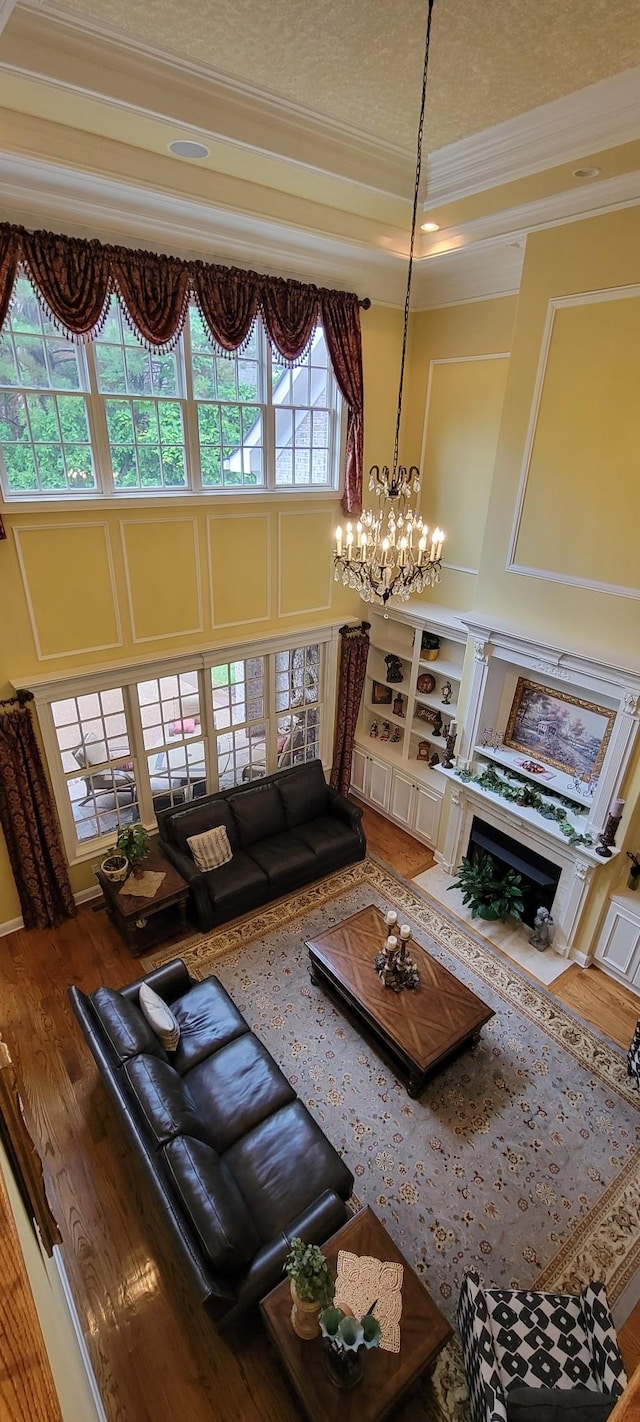 living room featuring a high ceiling, a high end fireplace, an inviting chandelier, and ornamental molding