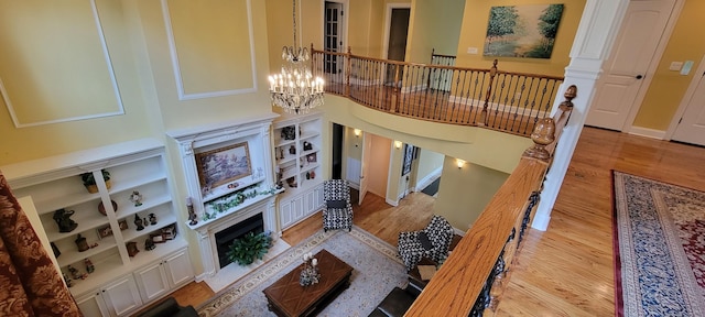 living room with light wood-type flooring, built in features, and a chandelier