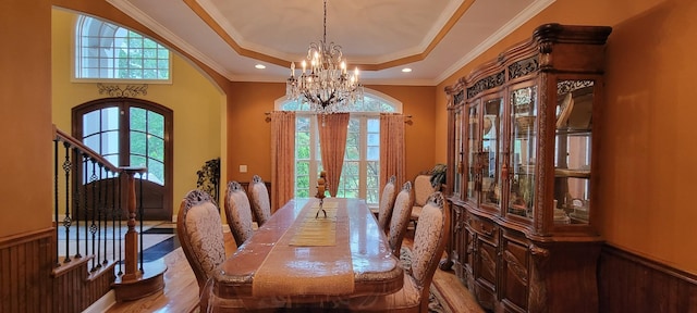 dining room with a notable chandelier, french doors, a tray ceiling, ornamental molding, and wood-type flooring