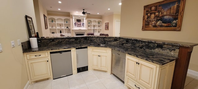 kitchen with stainless steel dishwasher, ceiling fan, dark stone counters, and cream cabinetry