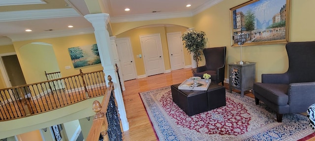 sitting room with ornate columns, wood-type flooring, and ornamental molding