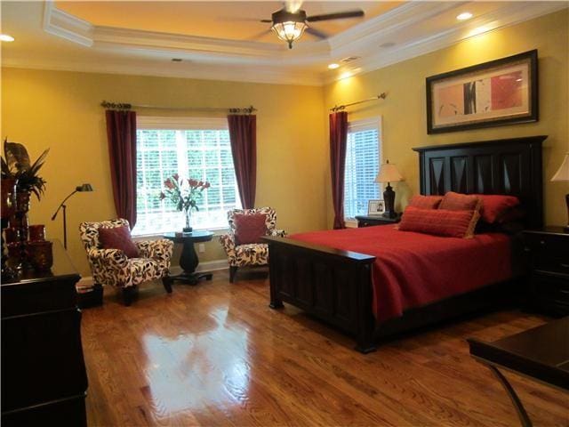 bedroom featuring hardwood / wood-style floors, ceiling fan, a tray ceiling, and crown molding