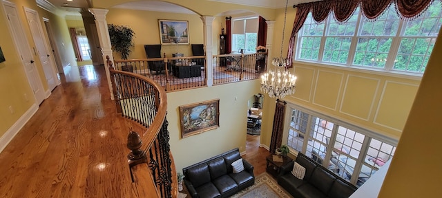 interior space with hardwood / wood-style floors, a notable chandelier, crown molding, and ornate columns