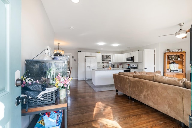 living room featuring dark hardwood / wood-style floors, ceiling fan, and sink