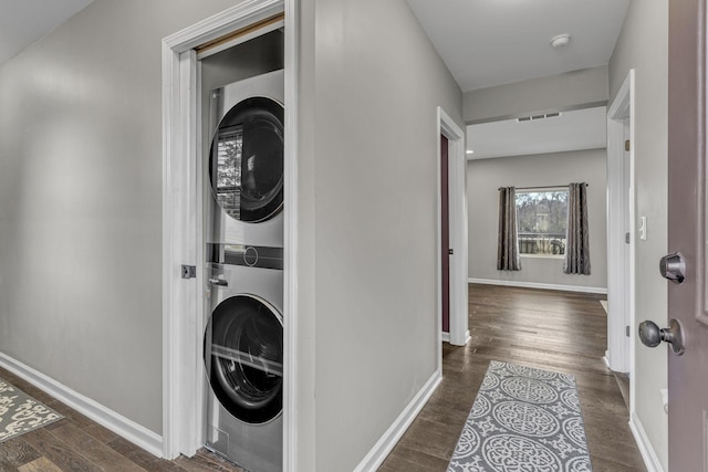 washroom with stacked washing maching and dryer and dark hardwood / wood-style floors