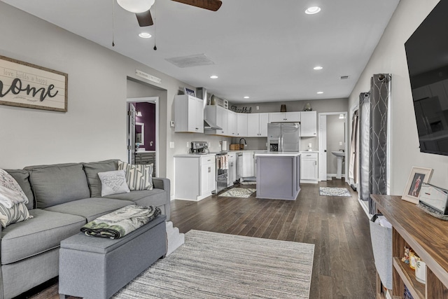 living room with ceiling fan, sink, and dark wood-type flooring