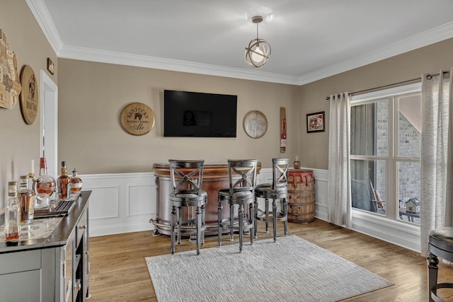 dining area featuring light hardwood / wood-style flooring, bar, and crown molding