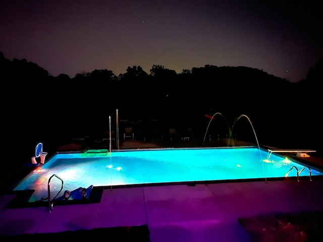 pool at twilight featuring pool water feature and a water slide