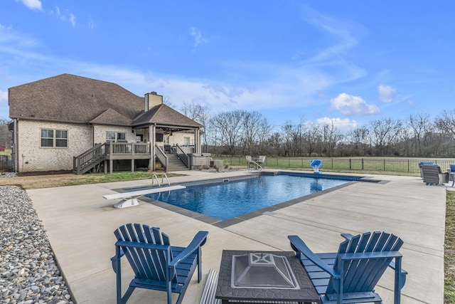 view of pool with a diving board, a patio, a deck, and an outdoor fire pit