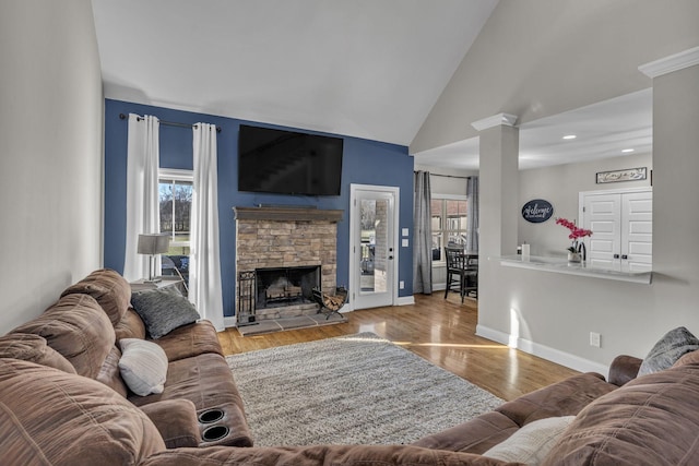 living room with vaulted ceiling, a fireplace, and light hardwood / wood-style flooring