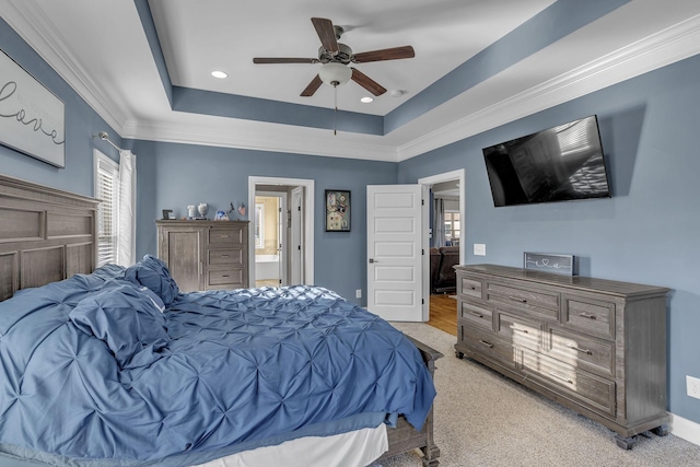 carpeted bedroom with a raised ceiling, ensuite bath, and ceiling fan