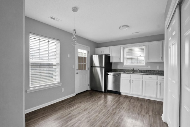 kitchen with dark hardwood / wood-style flooring, stainless steel appliances, sink, white cabinets, and hanging light fixtures