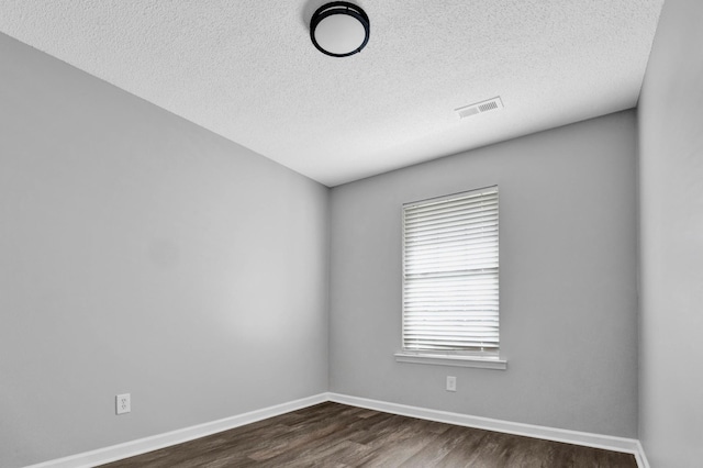 empty room with a textured ceiling and dark hardwood / wood-style floors