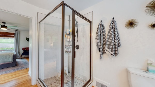 bathroom featuring ceiling fan, hardwood / wood-style floors, an enclosed shower, and toilet