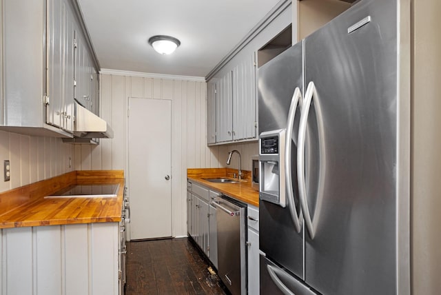 kitchen with butcher block counters, sink, stainless steel appliances, and ornamental molding