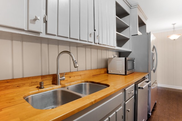 kitchen featuring white cabinets, decorative light fixtures, wood counters, and sink