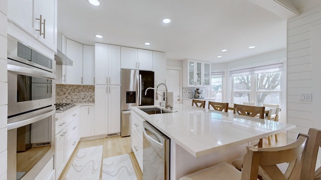 kitchen featuring appliances with stainless steel finishes, tasteful backsplash, a kitchen island with sink, sink, and white cabinetry