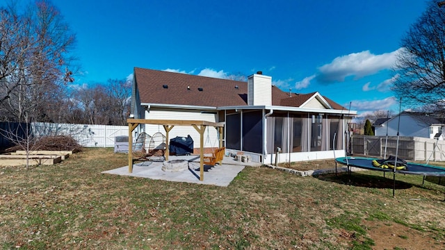 back of house with a sunroom, a patio area, a trampoline, and a yard