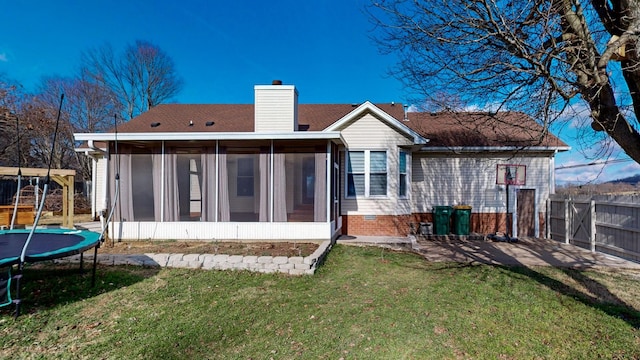 back of house with a lawn, a sunroom, and a trampoline