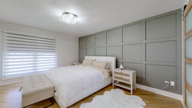 bedroom featuring a barn door and light wood-type flooring