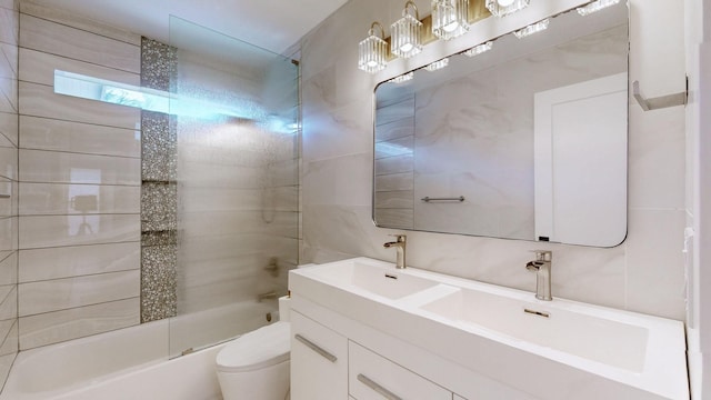 full bathroom featuring vanity, backsplash, tiled shower / bath, toilet, and tile walls