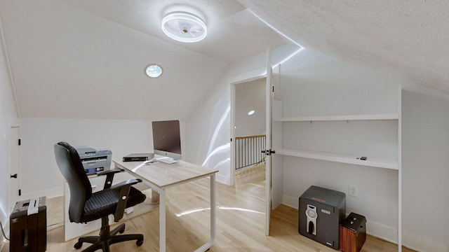 home office featuring lofted ceiling, a textured ceiling, and light hardwood / wood-style flooring