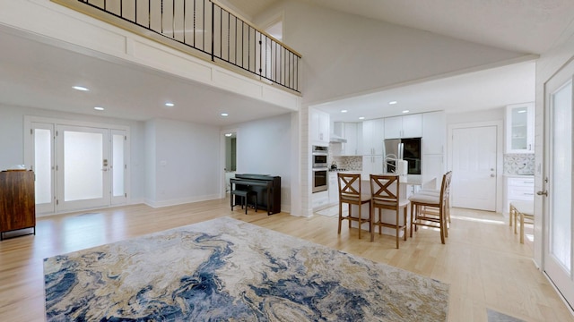 living room featuring light wood-type flooring and high vaulted ceiling