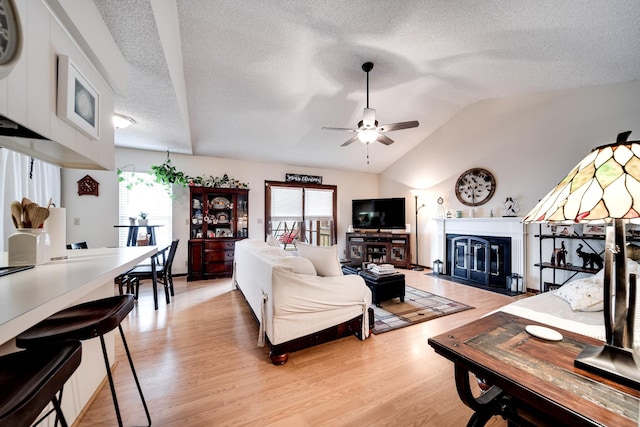 living room featuring ceiling fan, plenty of natural light, light hardwood / wood-style floors, and vaulted ceiling