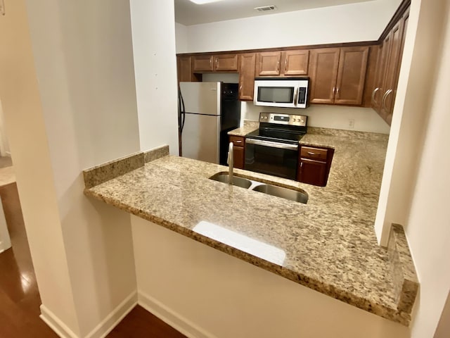 kitchen with light stone counters, kitchen peninsula, and stainless steel appliances