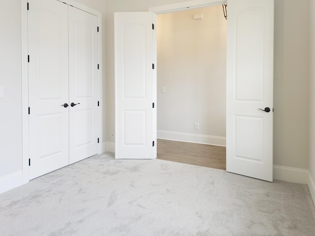 unfurnished bedroom with light colored carpet and a closet