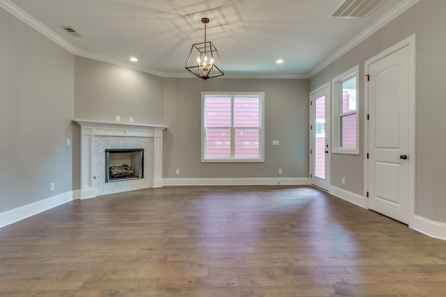 unfurnished living room featuring dark hardwood / wood-style flooring, a fireplace, ornamental molding, and an inviting chandelier