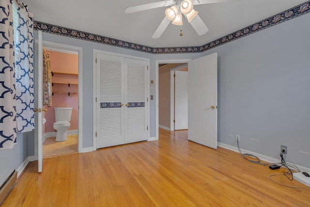 unfurnished bedroom with ensuite bath, ceiling fan, baseboard heating, a closet, and light wood-type flooring