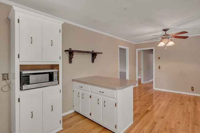 kitchen featuring kitchen peninsula, ceiling fan, light wood-type flooring, ornamental molding, and white cabinetry