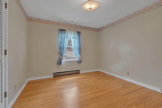 unfurnished room featuring hardwood / wood-style flooring and a baseboard heating unit