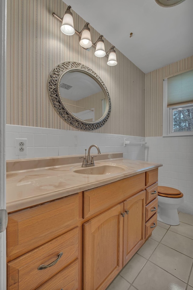 bathroom featuring tile patterned floors, vanity, toilet, and tile walls