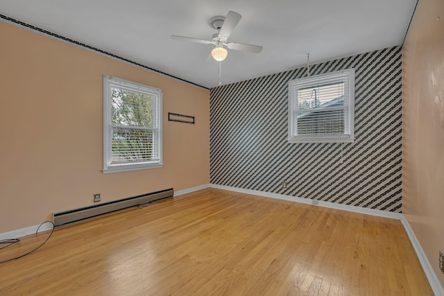 unfurnished room featuring a baseboard radiator, light hardwood / wood-style flooring, and a healthy amount of sunlight