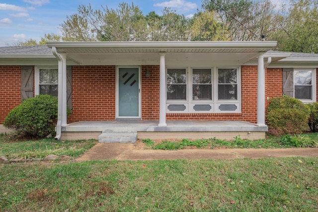 doorway to property with a lawn and covered porch