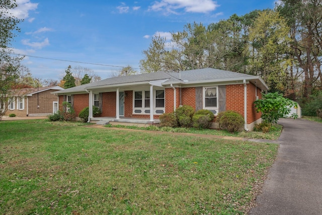 ranch-style house featuring covered porch and a front lawn