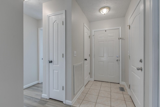 doorway to outside with light tile patterned floors and a textured ceiling