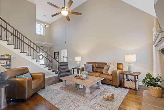 living room with a towering ceiling, ceiling fan with notable chandelier, and hardwood / wood-style flooring