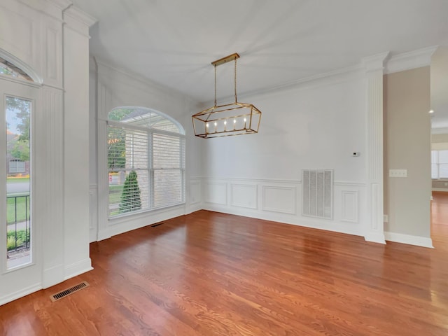 spare room with hardwood / wood-style flooring, a notable chandelier, and ornamental molding