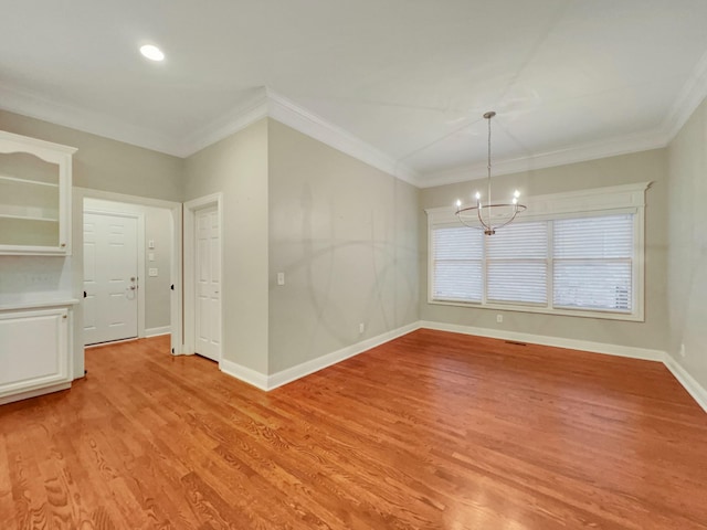 spare room featuring crown molding, light hardwood / wood-style flooring, and a chandelier