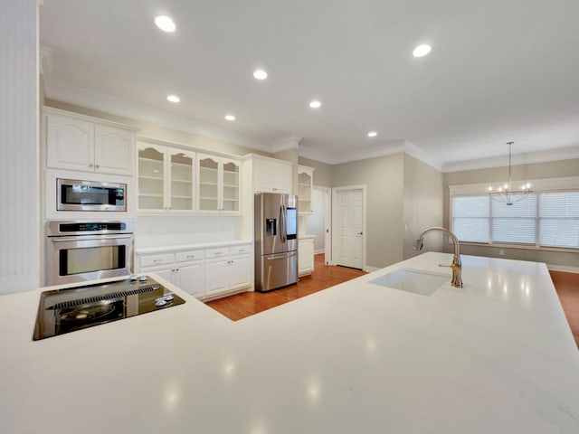 kitchen with sink, a chandelier, decorative light fixtures, white cabinets, and appliances with stainless steel finishes