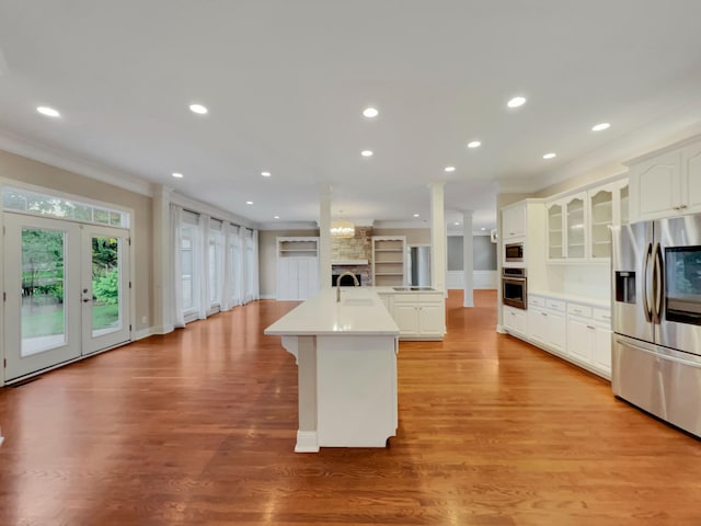 kitchen with stainless steel appliances, white cabinetry, a kitchen island with sink, and light hardwood / wood-style floors