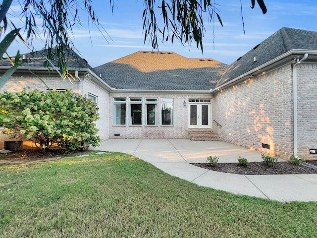 rear view of house featuring french doors, a patio, and a lawn