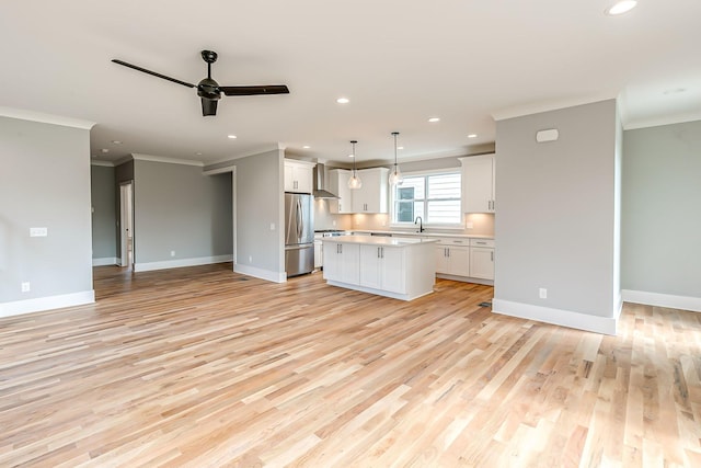 kitchen with light wood-type flooring, decorative light fixtures, white cabinetry, a kitchen island, and stainless steel refrigerator