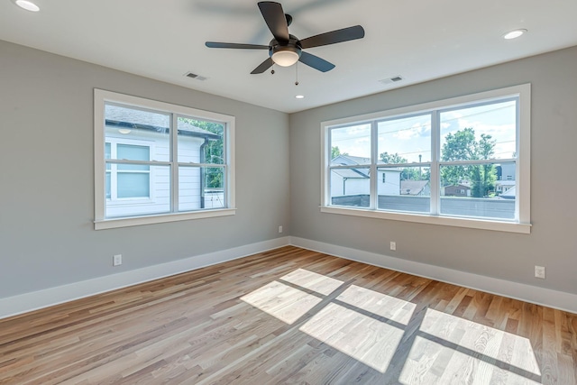 spare room featuring a wealth of natural light, ceiling fan, and light wood-type flooring